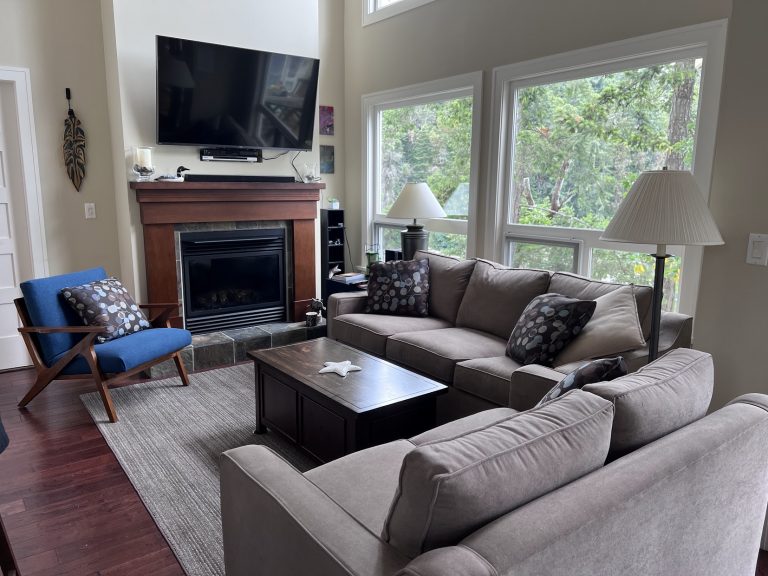 Living room at Cottage 12 with smart TV, fireplace, and large windows overlooking Otter Bay Marina
